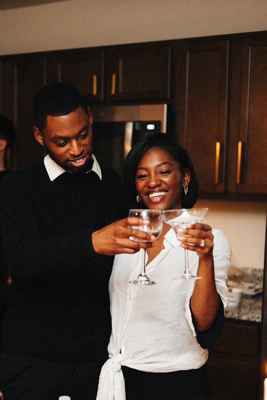 A dressed-up couple laughing as they toast